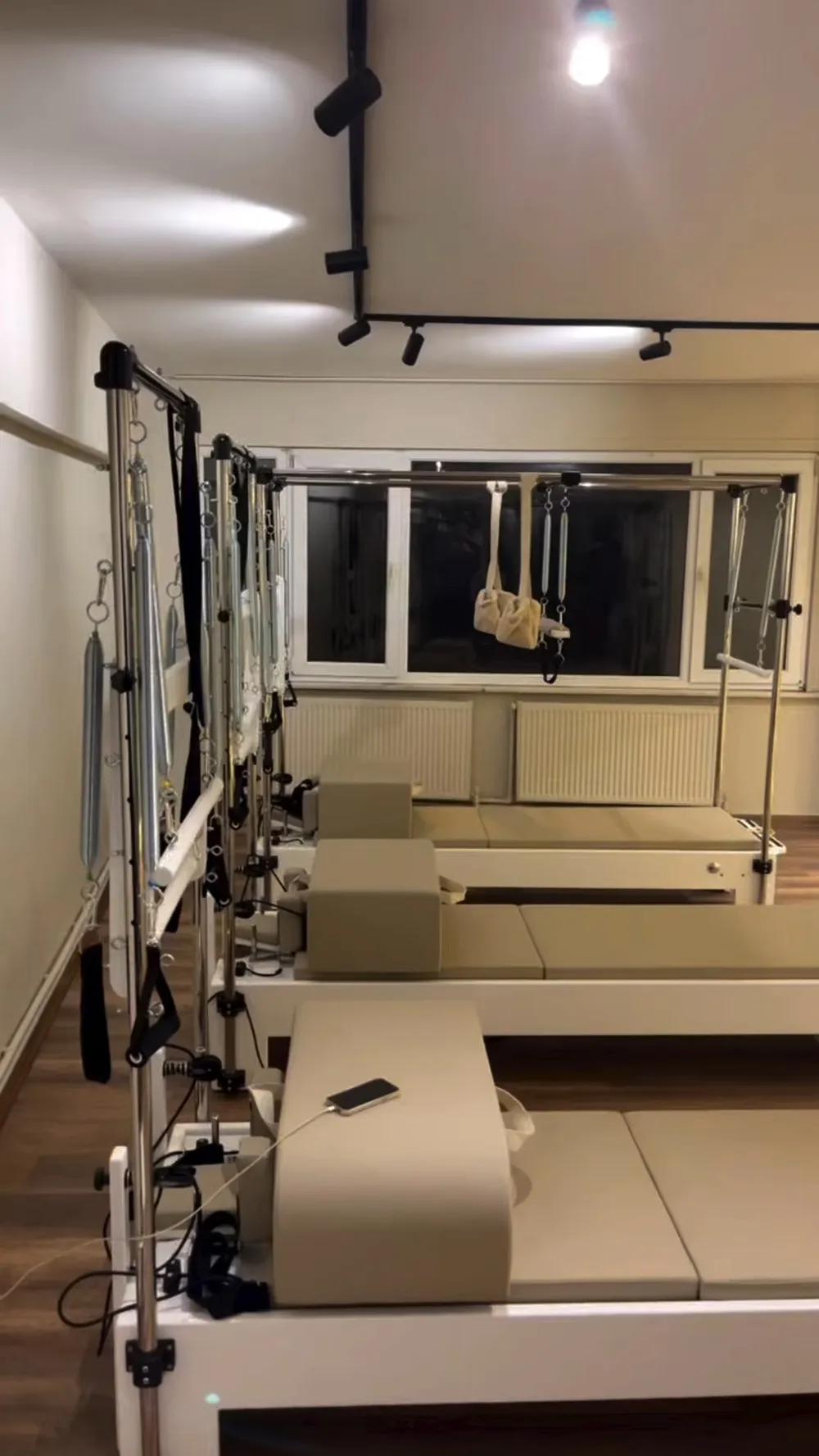 Novexa stüdyosunda sıralanmış reformer pilates aletleri, parke zemin ve ray spotlar